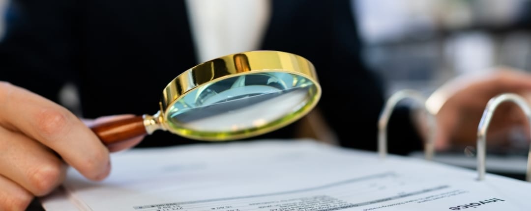 Business professional examining financial documents with a magnifying glass during a SARS audit.