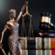 Lady Justice statue beside law books and gavel symbolizing legal reform.