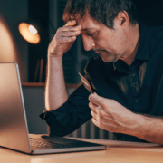 Stressed man reviewing finances on laptop, concerned about issues with foreign bank account and SARS tax refunds. - foreign bank account