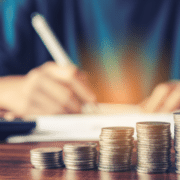 Stacked coins next to an individual who is calculating their VAT post budget speech 2026 - Budget 2026 VAT lever